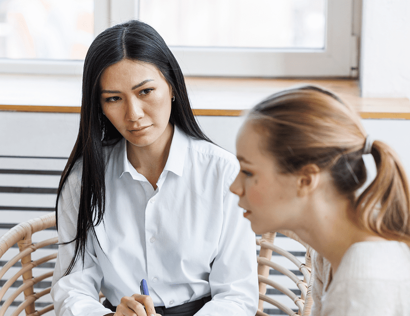Two women engaged in a serious conversation indoors.