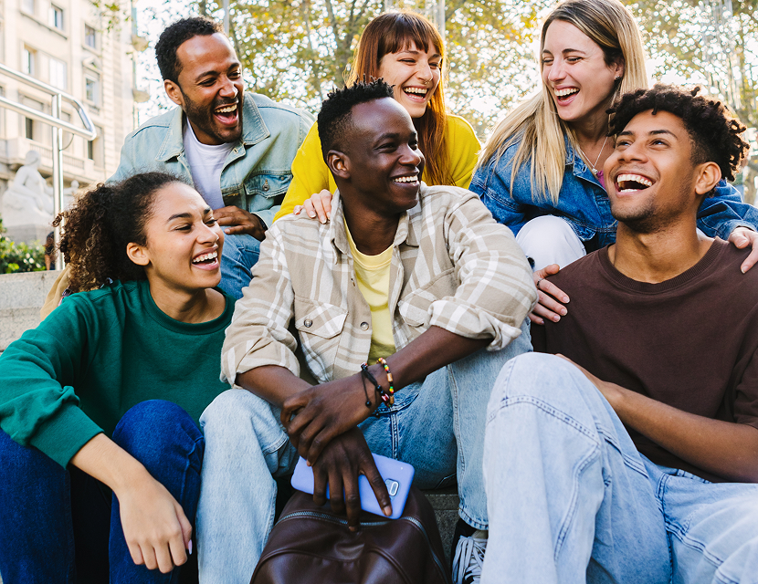 A group of diverse friends laughing and enjoying each other's company outdoors.