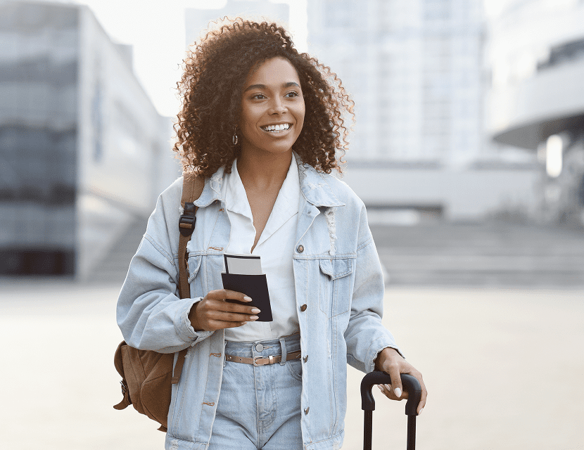 Young woman traveling with coffee and luggage in the city.