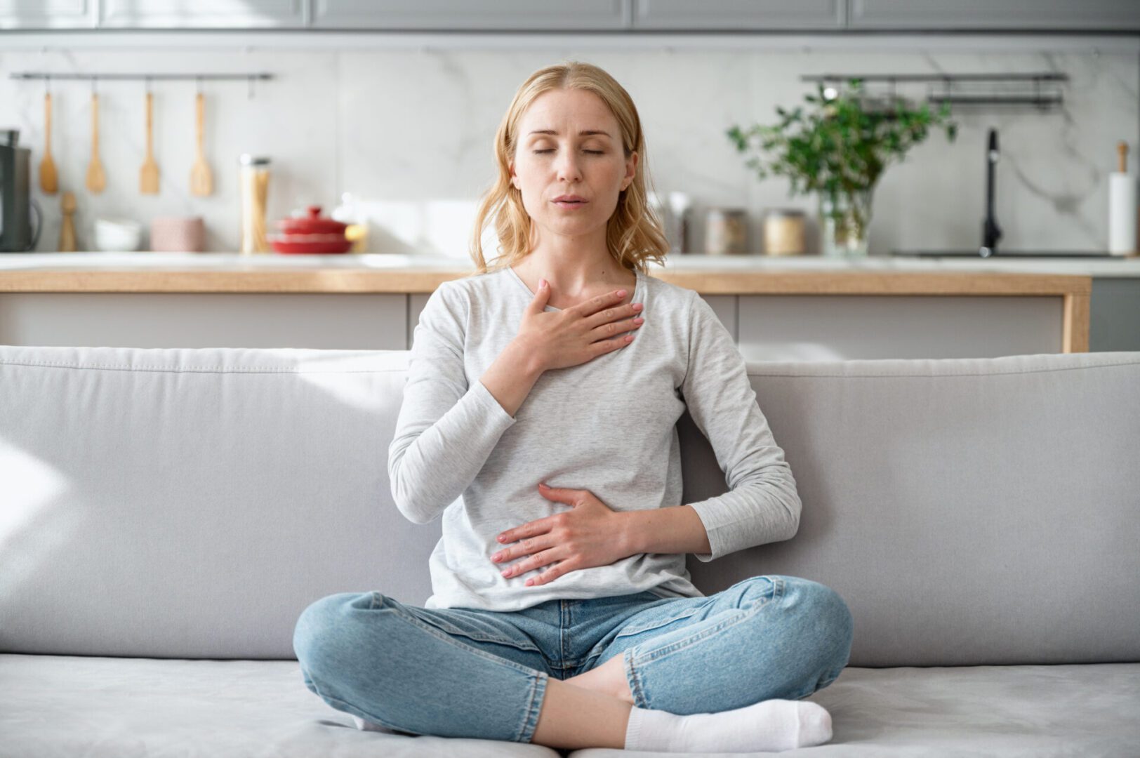 Woman meditating on sofa, practicing mindfulness.