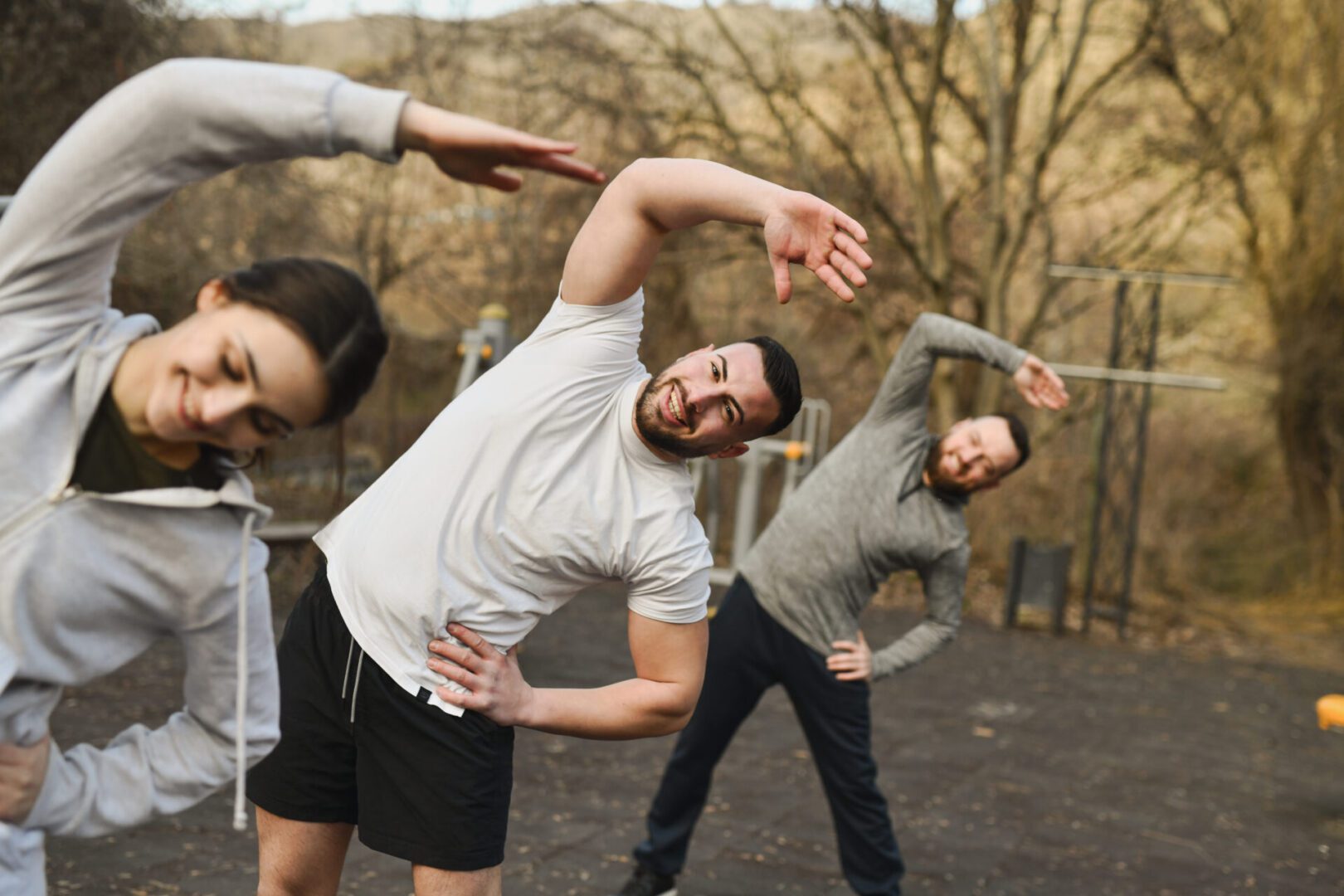 People exercising outdoors, stretching side to side.