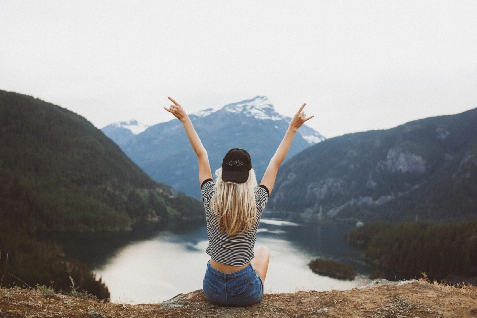 Person celebrating on mountain with scenic view.