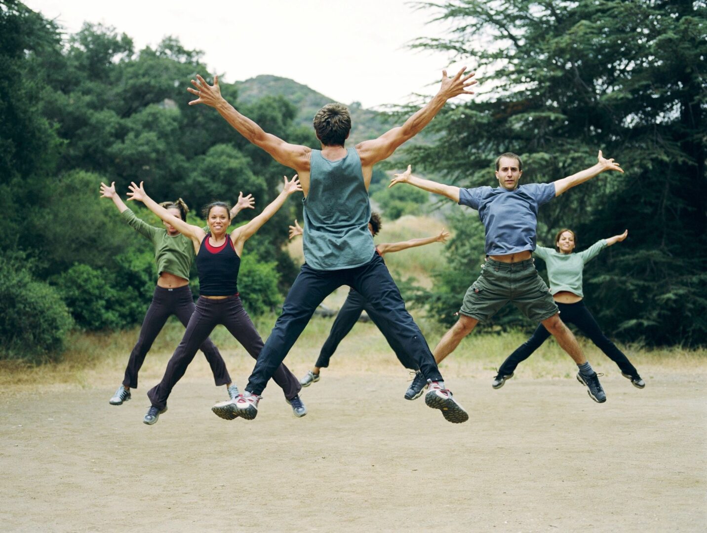 Group exercising outdoors with jumping jacks.