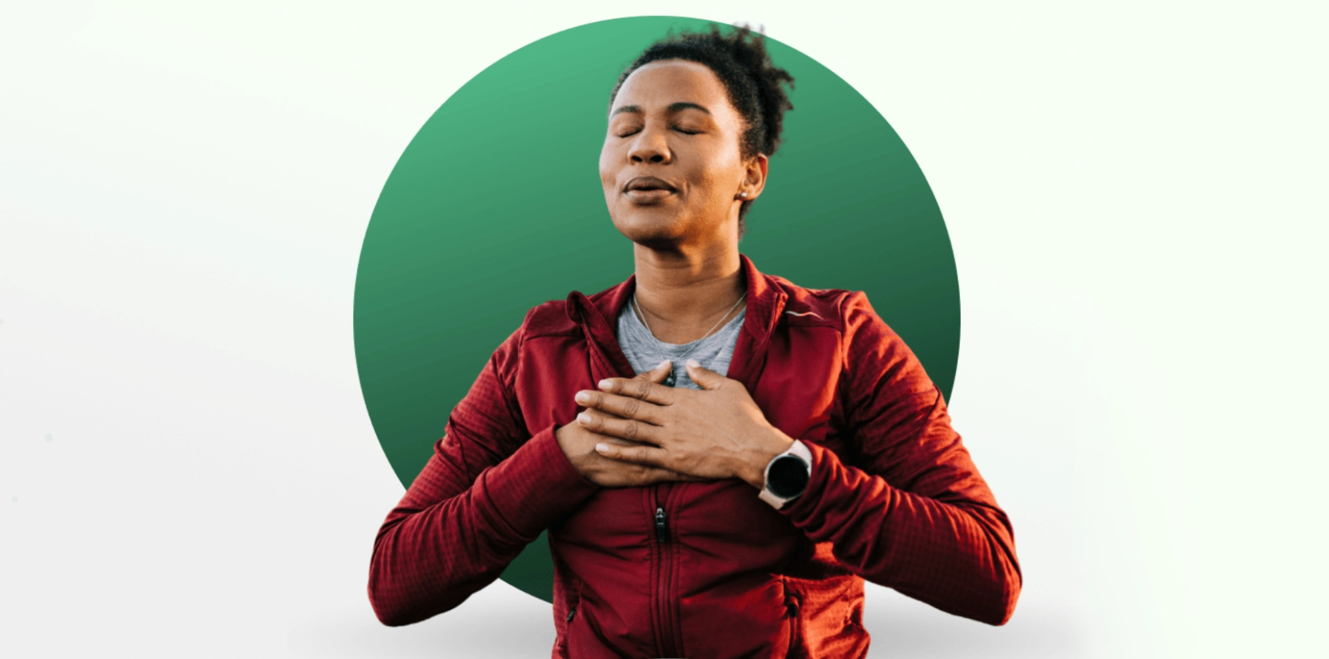 Person in red jacket meditating with eyes closed and hands on chest.