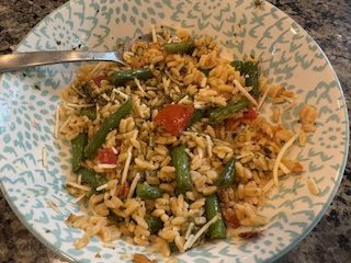 A bowl of vegetable fried rice with green beans and tomatoes.