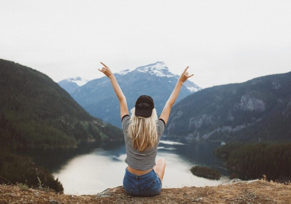 Person celebrating on mountain with scenic view.